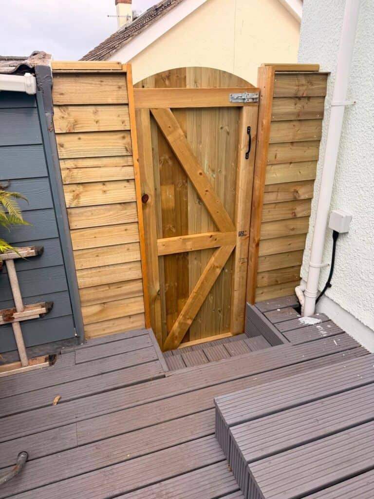 Wooden garden gate with latch and hinges in a backyard setting.